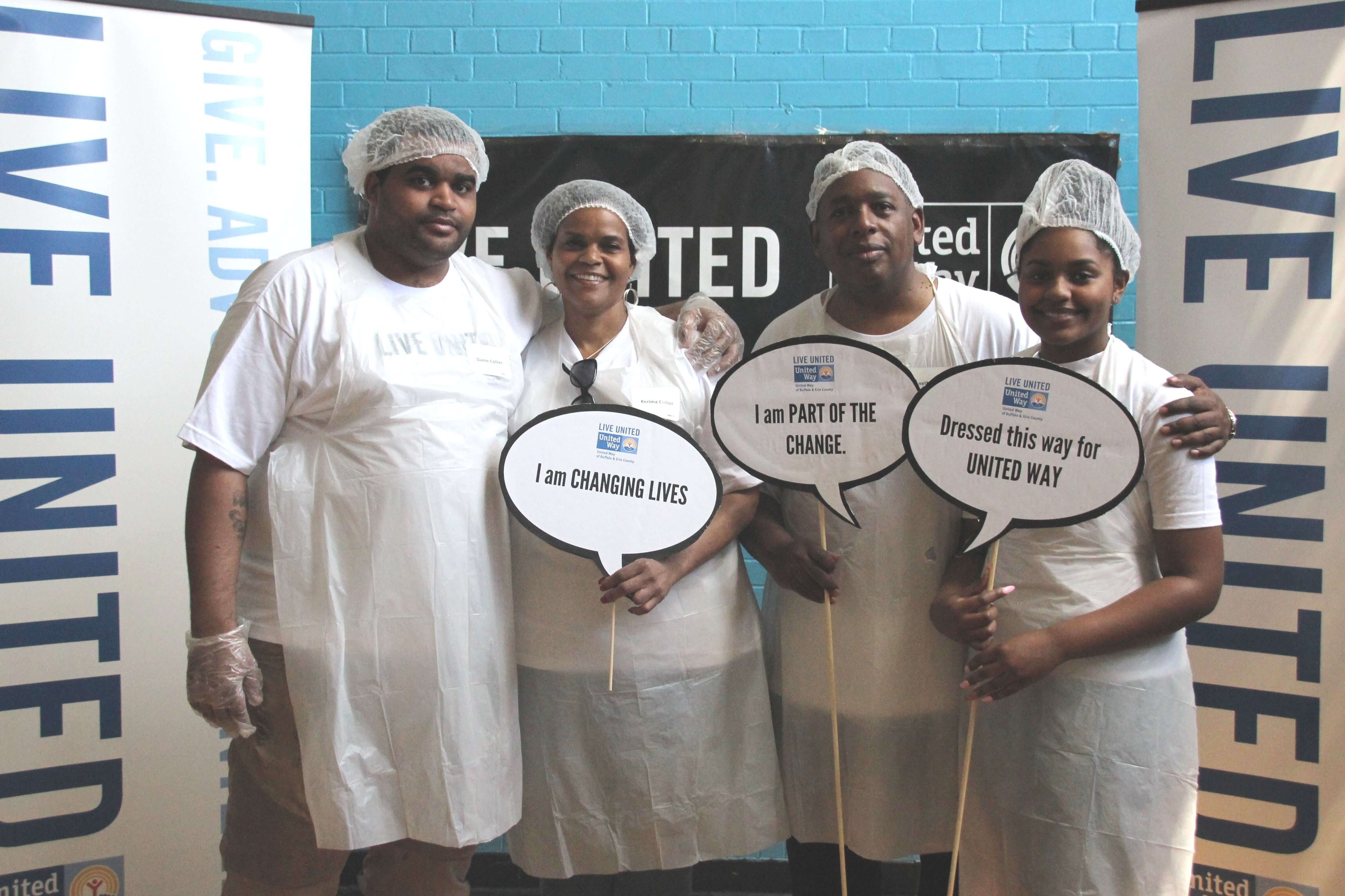 Four adult volunteers holding signs 