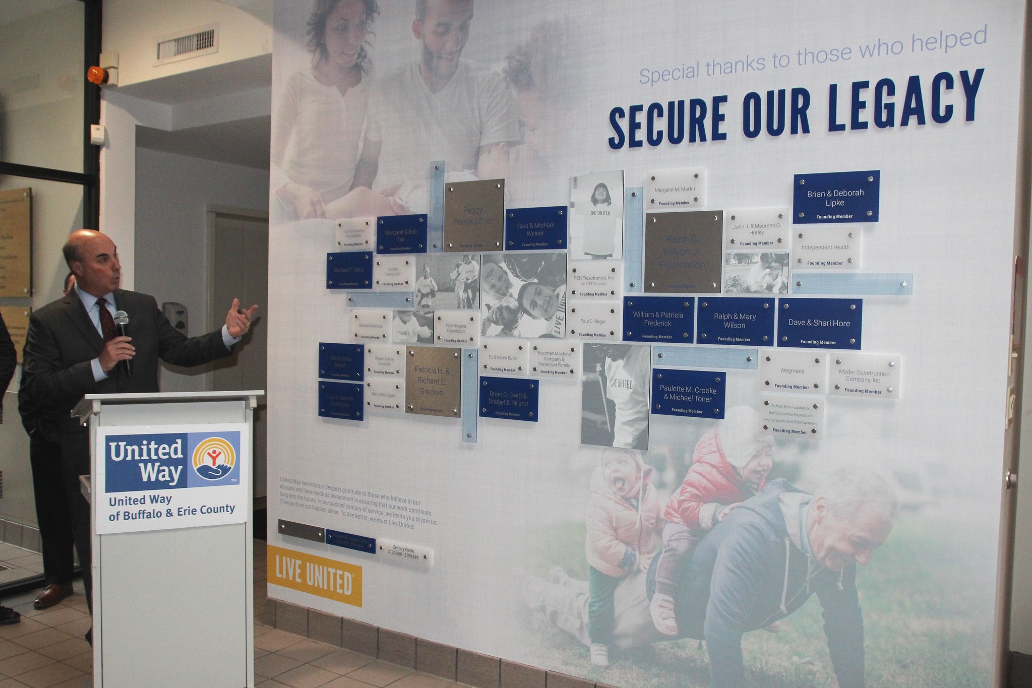 President and CEO Michael Weiner standing with the UWBEC donation acknowledgement wall